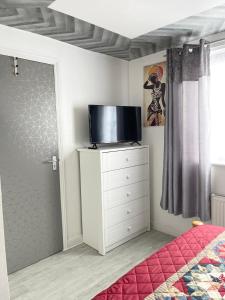 a bedroom with a tv on top of a dresser at Westfield Gardens - 3 Bedroom Apartment in Goodmayes