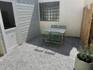 a patio with a table and chairs and a door at appartement 50 mètres de la mer in Jullouville-les-Pins