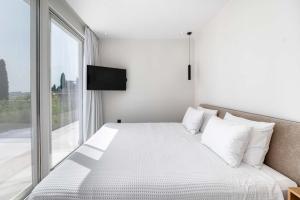a bedroom with a white bed with a large window at Villa Lazareto in Kontokali +57 photos