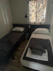 een slaapkamer met twee bedden en een raam met een gordijn bij Paradiso mobile home in Biograd na Moru