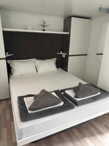 een slaapkamer met een wit bed met 2 kussens erop bij Paradiso mobile home in Biograd na Moru