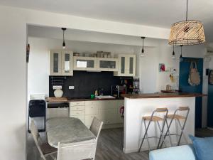 a kitchen with white cabinets and a table and chairs at Face Mer 2 chambres parking in Hossegor