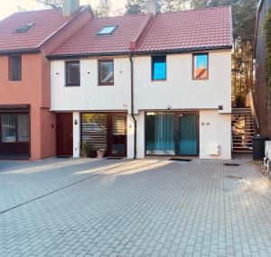 a house with a brick driveway in front of it at Poilsis Nidoje -LA ISLA DE NIDA- Su terasa in Nida
