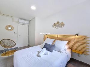 a bedroom with a large white bed with a wooden headboard at Douceur Exotique - 2 chambres - piscine partagée - centre-ville de Saint-Pierre in Saint-Pierre +15 photos