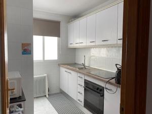 Una cocina blanca con fregadero y estufa. en Central Puerto, en Puerto de Mazarrón