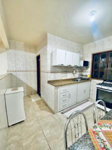 a kitchen with white cabinets and a white refrigerator at Casa e Kitnet - Praia Grande Centro in Arraial do Cabo