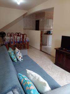 a living room with a blue couch and a kitchen at Casa e Kitnet - Praia Grande Centro in Arraial do Cabo