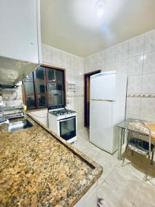 a kitchen with a stove and a white refrigerator at Casa e Kitnet - Praia Grande Centro in Arraial do Cabo +19 photos