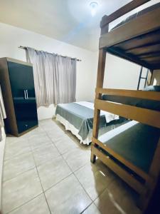 a bedroom with a bunk bed and a television at Casa e Kitnet - Praia Grande Centro in Arraial do Cabo