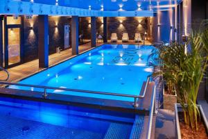 a large pool with blue water in a building at OKRA RESORT & SPA in Drawsko Pomorskie