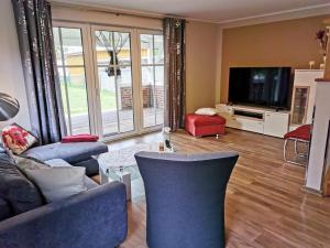 a living room with blue couches and a tv at Haus Kranichweide in Bodstedt