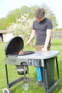 a man is cooking food on a grill at Le Cocon des Layes classé officiellement 5 étoiles in Les Essarts-le-Roi