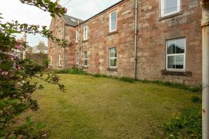an old brick building with a grass yard at Wellington Lodge in Ayr