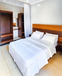 a bedroom with a large bed with white sheets at Victors Valley Hotel in Nakwero