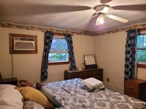 een slaapkamer met een plafondventilator en een bed bij Lake Congamond Suffield House in Granby