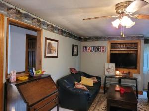 een woonkamer met een leren bank en een televisie bij Lake Congamond Suffield House in Granby