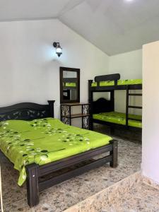 una camera da letto con un letto con una coperta verde sopra di HOSPEDAJE CAMPESTRE VILLA PARAISO a Curití