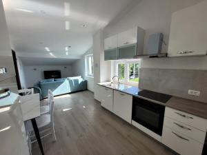cocina con armarios blancos y sofá azul en Apartman Andy, en Matulji