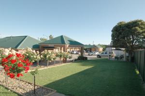 a yard with flowers and a building in the background at Poachers Paradise in Rutherglen