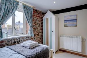 une chambre avec un lit et un mur de briques dans l'établissement Natterjack by Winterton Cottages, à Winterton-on-Sea