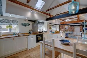 une cuisine avec des armoires blanches et une table en bois dans l'établissement Natterjack by Winterton Cottages, à Winterton-on-Sea