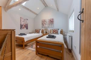 2 Betten in einem Zimmer mit weißen Wänden und Holzböden in der Unterkunft The Cow Stalls - Stunning Farmhouse with Wonderful Views and Garden - Close to Corfe Castle in Langton Matravers