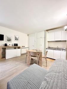 a bedroom with a table and a kitchen with white cabinets at Tonale Ski-in AlpView Studio in Passo del Tonale