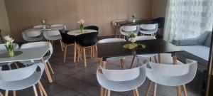 un restaurante con mesas blancas y sillas blancas en SM Africa Guest House, en Alberton