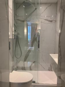 a bathroom with a glass shower with a toilet at H&ocirc;tel de France Quartier Latin in Paris