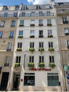 a white building with windows and potted plants on it at H&ocirc;tel de France Quartier Latin in Paris
