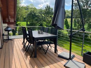 a table and chairs on a deck with an umbrella at Chez Ellie- Ferienwohnung Nähe Nürburgring, Rhein, Ahr, Eifel in Kempenich