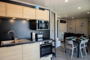 a kitchen with a sink and a table with chairs at Escales Voyages Cottage des Dunes - Chalet de 49m2 climatisé - 6 personnes in Jullouville-les-Pins