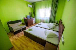 ein grünes Zimmer mit zwei Betten und einem Stuhl in der Unterkunft Pensiunea Domneasca in Piteşti + 45 Fotos