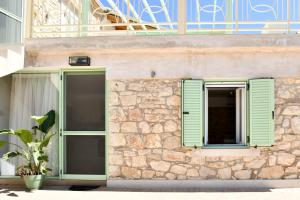 a building with green shutters and a potted plant at Captain theo apartment Annoula in Lefkímmi