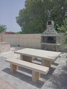 a picnic table with a pizza oven behind it at Kuća za odmor Mira blizu Biograda na moru in Donja Jagodnja