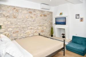 a bedroom with a stone wall with a bed and a blue chair at Captain theo apartment Annoula in Lefkímmi