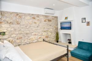 a room with a stone wall with a couch and a tv at Captain theo apartment Annoula in Lefkímmi