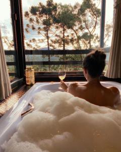 a man sitting in a bath tub with a glass of wine at Vale Dourado Cabanas in Urubici