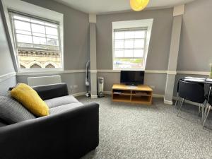 a living room with a couch and a tv and two windows at Super Central Apartment in Heart of the City in Bristol