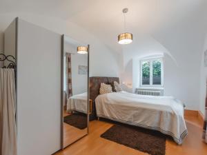 Un dormitorio blanco con una cama y un espejo. en Apartment Rübezahl-1 by Interhome, en Bad Hofgastein
