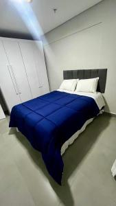 Cama en habitación con manta azul en Diamond Flats 305 - São Lourenço, en São Lourenço 8 fotos más