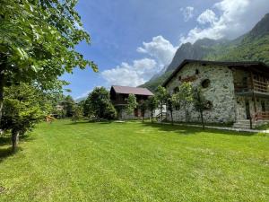a house with a grass yard next to a building at Valbona Relax in Valbonë +64 photos