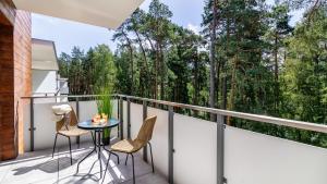 ステグナにあるSTEGNA PARK II blisko plaży Apartamenty Piamolaの木々が植わるバルコニー(テーブル、椅子付)