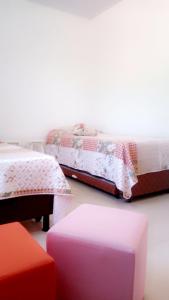 a room with two beds and a table and a stool at Escondidinho da Serra in Serra Negra
