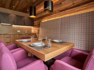 a wooden table with purple chairs and a table with plates at Holiday Home Bergsteiger - Chalet by Interhome in Sölden