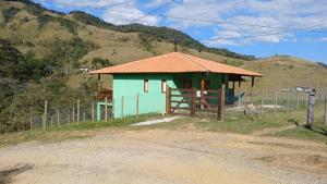 a small green building with a fence in front of a mountain at Casa em São Francisco Xavier sp in São Francisco Xavier