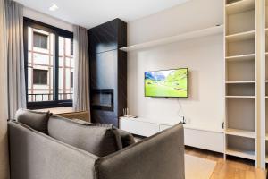 a living room with a couch and a television at Blume Garden 1 dorm by Achei Gramado in Gramado