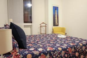 a bedroom with a bed with a flowered blanket and a yellow chair at Gioiella pool lake pet friendlyBy Case al Lago in Desenzano del Garda +27 photos