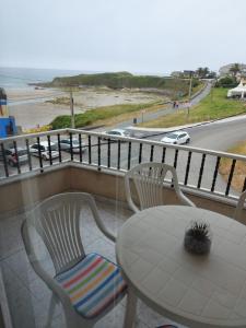 Una mesa y sillas en un balcón con vista a la playa. en Vivienda PLAYA DE ALTAR, en Barreiros