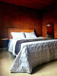 a large bed in a bedroom with a brick wall at Casa na Rampa - Hospedagem no Caravaggio in Santa Teresa